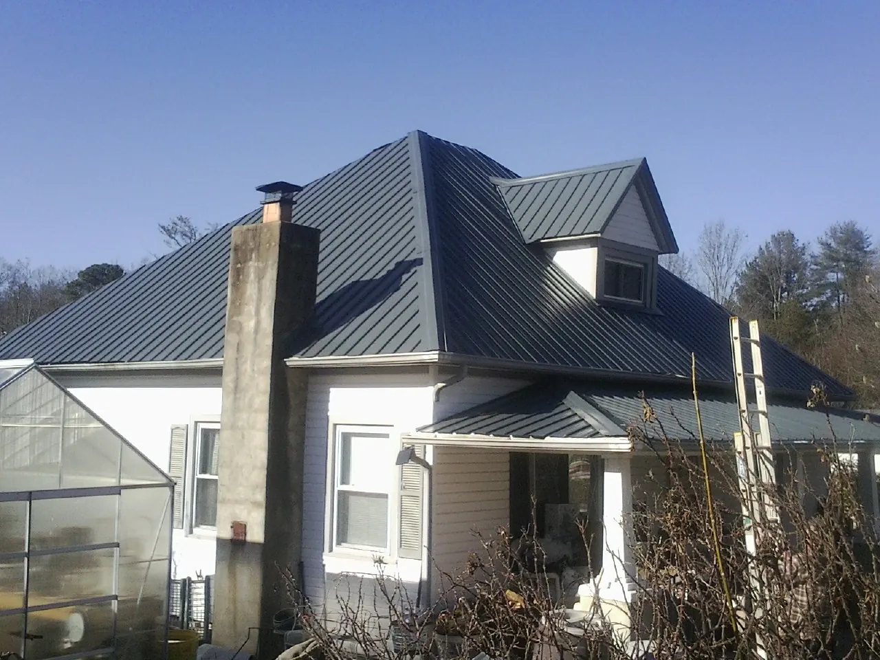 Dark blue standing seam metal roof on a white farmhouse with dormer — Slate & Tile Roof Repair by Roofing Brothers in Escondido