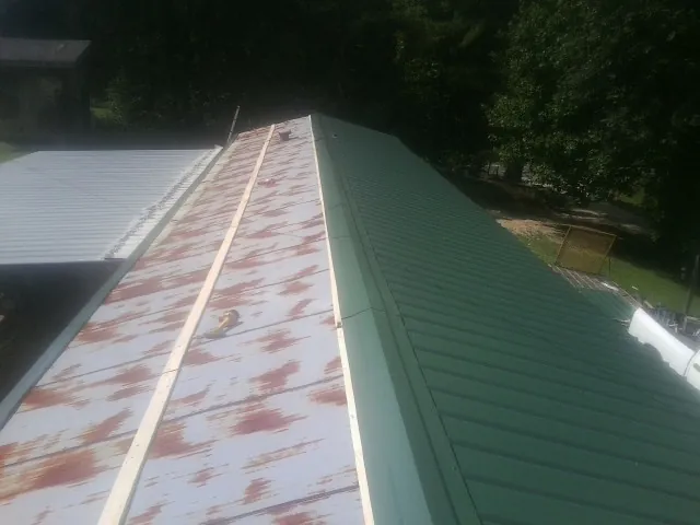 Old rusted panels beside newly installed green metal roofing — Wind Damage Roof Repair by Roofing Brothers in Escondido
