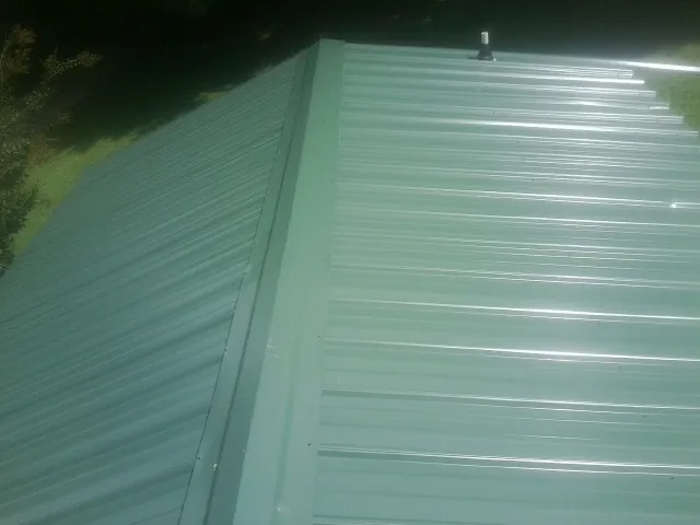New green metal panels meeting at the ridge of a roof — Flat Roof Repair work by our crew in Escondido