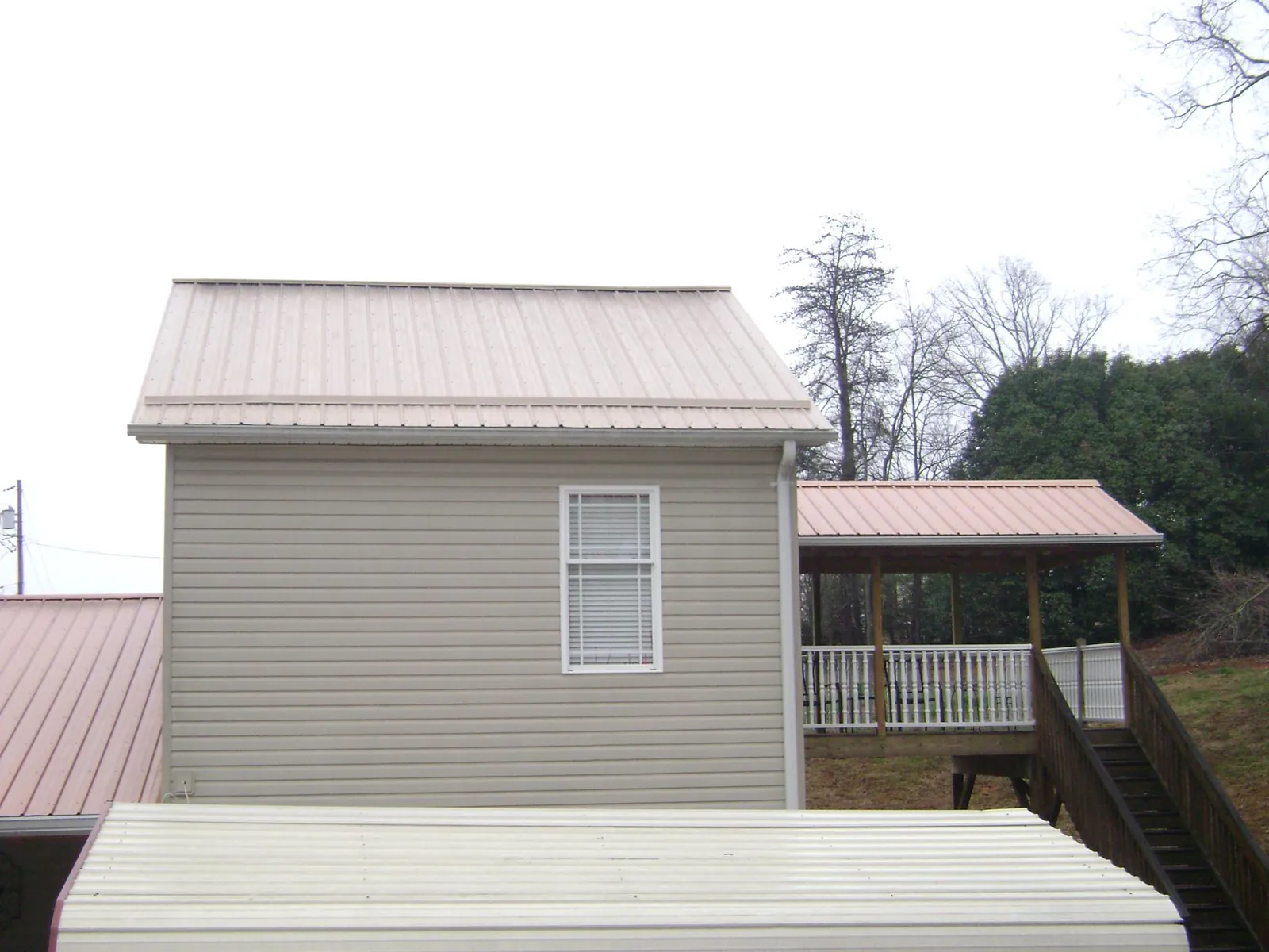Tan metal roofs on a two story addition and attached porch, from a Roof Replacement job in Escondido