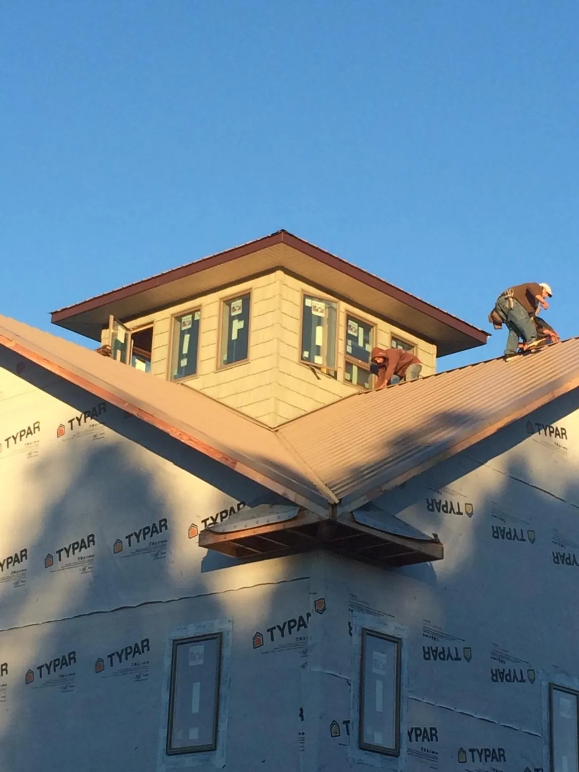 Roofers working around a rooftop cupola on a new metal roof at sunset — Roof Waterproofing in Escondido by Roofing Brothers